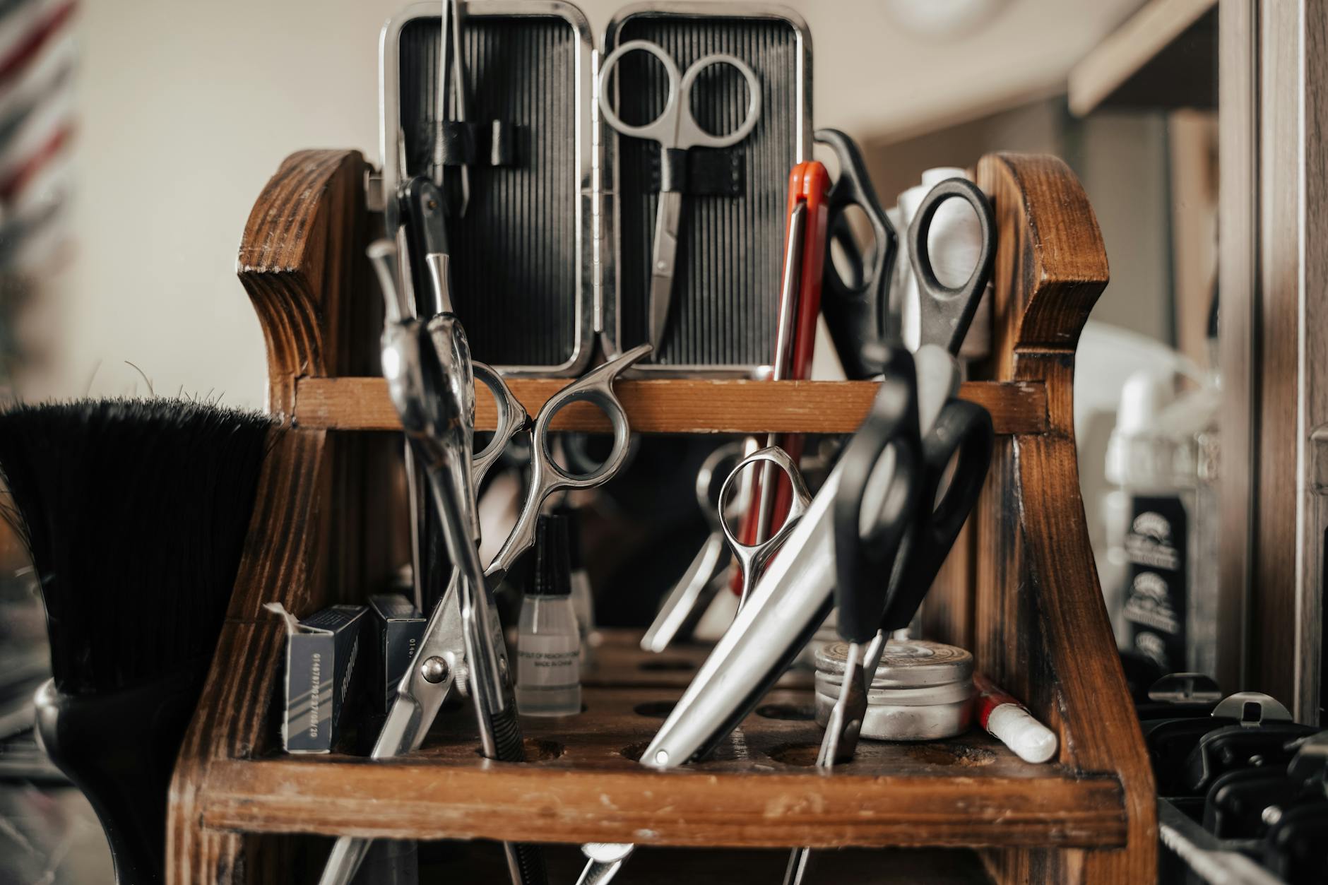 A close-up view of various barber tools on a wooden shelf in a barbershop.